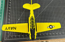 Yellow model airplane with 'NAVY' on a cutting mat