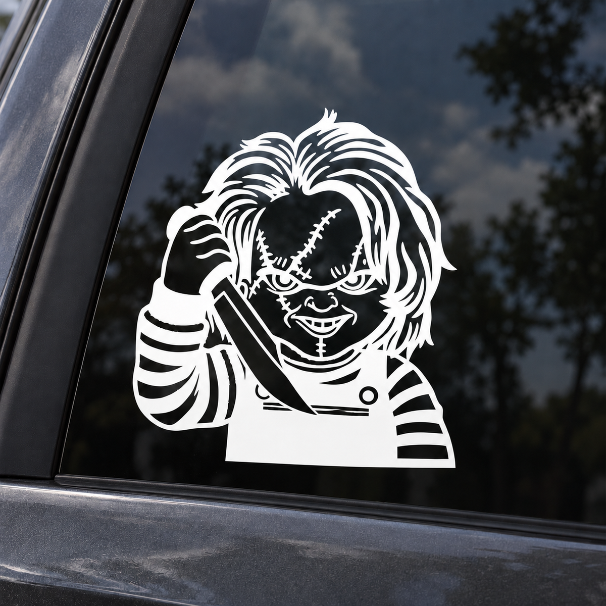 White Chucky contour-cut decal on dark tinted car window, with open interior spaces