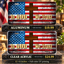 In God We Trust American Flag Cross License Plate Car Tag — aluminum $19.99 and ⅛-inch clear acrylic $24.99 material comparison